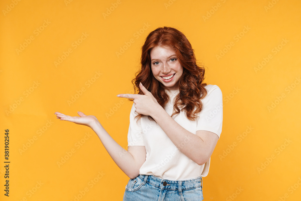 Image of ginger joyful girl holding and pointing finger at copyspace Image of ginger joyful girl holding and pointing finger at copyspace