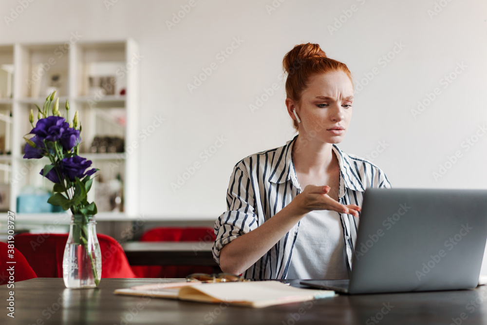 Attractive young redheaded woman using laptop
