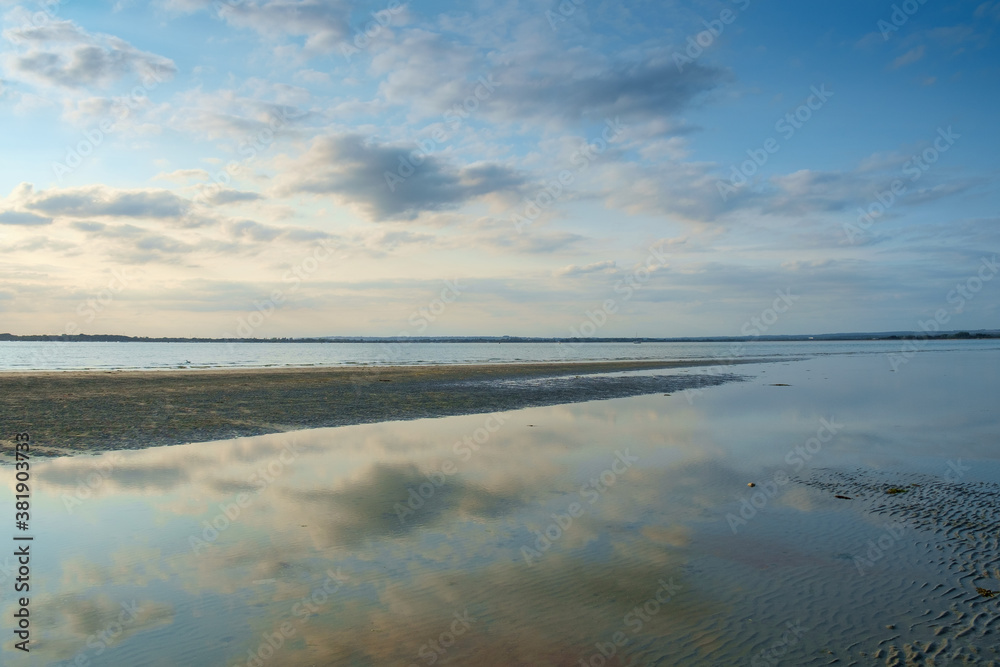 Blue sky and a calm sea in this tranquil evening view of Chichester Harbour from West Wittering beach, West Sussex, England, UK.