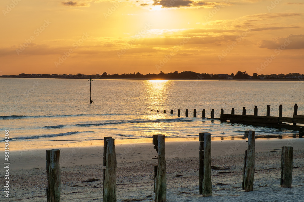 Sunset at East Head, West Wittering, Chichester Harbour, England. A golden sky and calm sea make a tranquil evening scene.