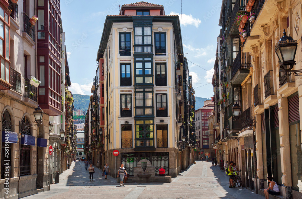 Bilbao, Spain: the old centre of Bilbao (barrio viejo), a pedestrian shopping zone with only a few people walking the sunlit streets because of siesta