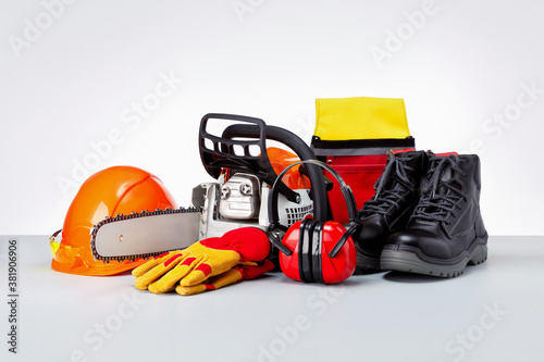 Chainsaw and protective clothes of lumberjack on grey surface. photo
