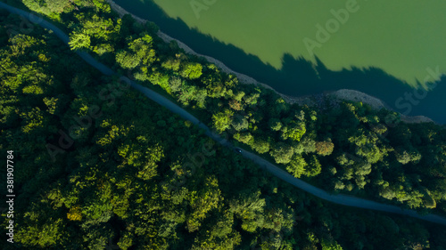 road under forest near a lake, aerial view in the daytime