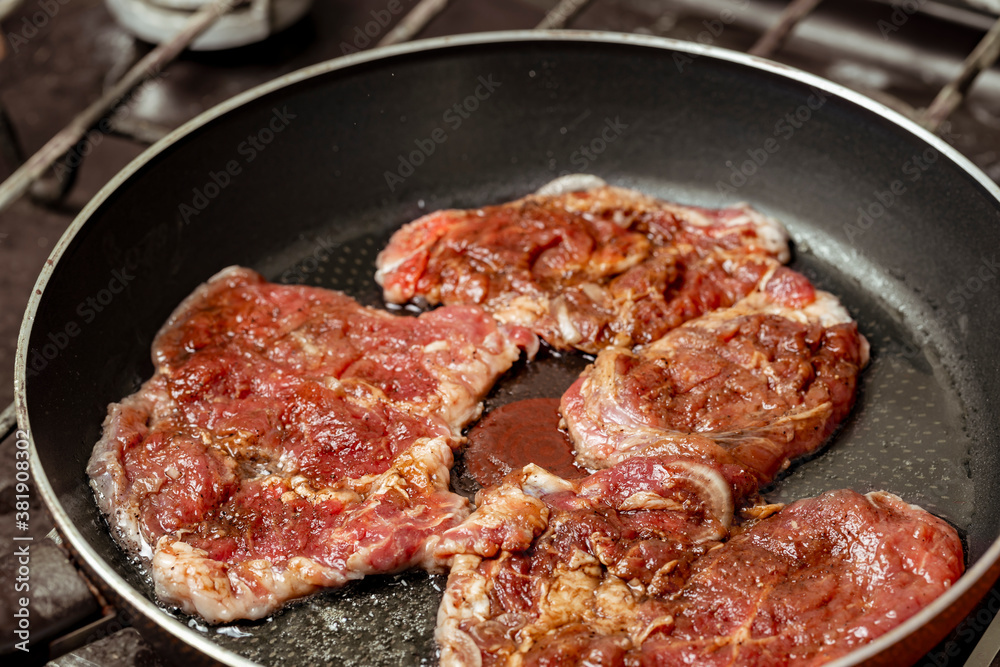 Beefsteaks are fried in a pan. Frying fresh beef. Hot meat in a frying pan.