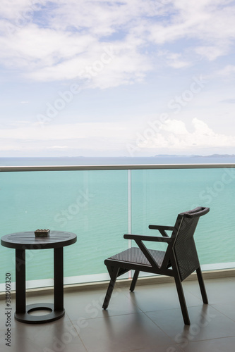 Table and chair with outdoor balcony and sea .The chair and table on balcony sea view. Chair with table set on balcony hotel room with ocean view background. © kanpisut