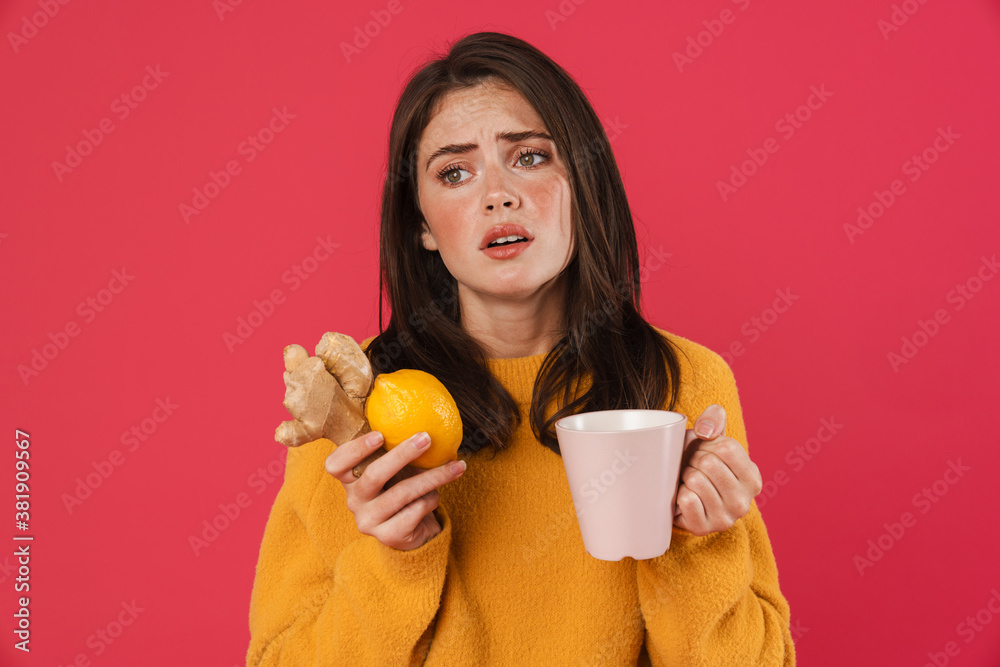Image of unhappy girl holding lemon and ginger while drinking tea Image of unhappy girl holding lemon and ginger while drinking tea