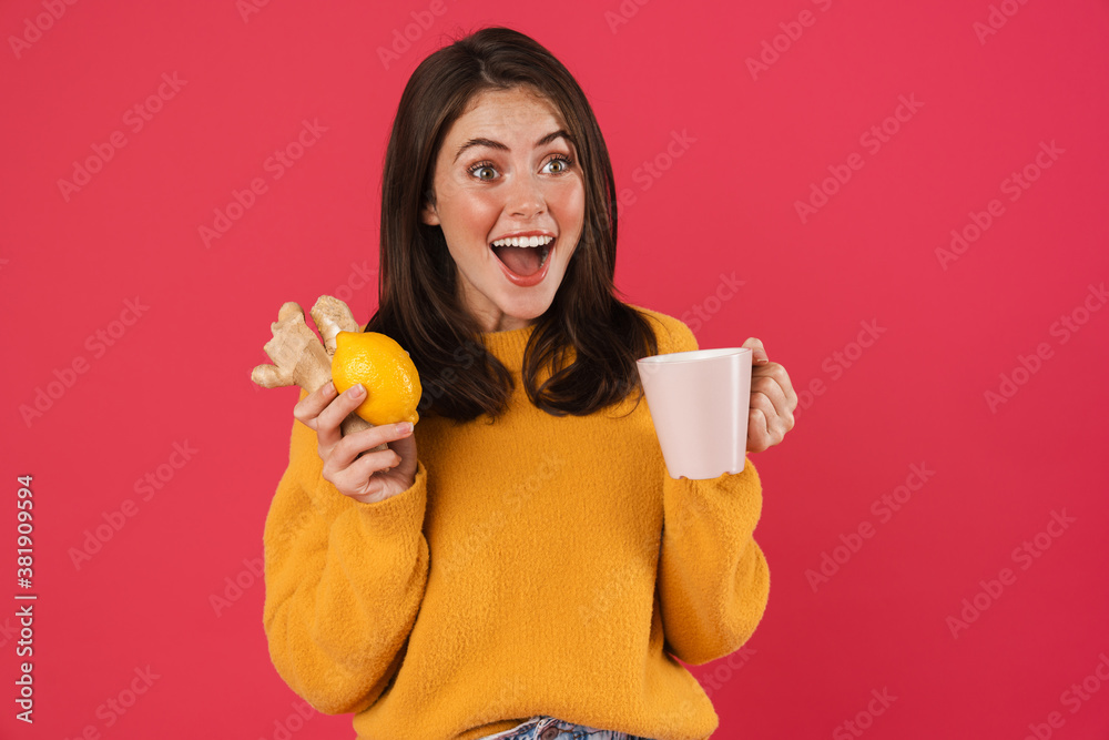Image of excited girl holding lemon and ginger while drinking tea Image of excited girl holding lemon and ginger while drinking tea