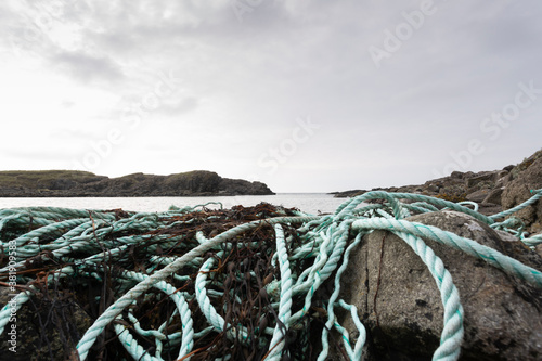 Debris from fishing industry washed up on rocks, nylon and plastic rope and netting is a major problem around all shorelines of the planet