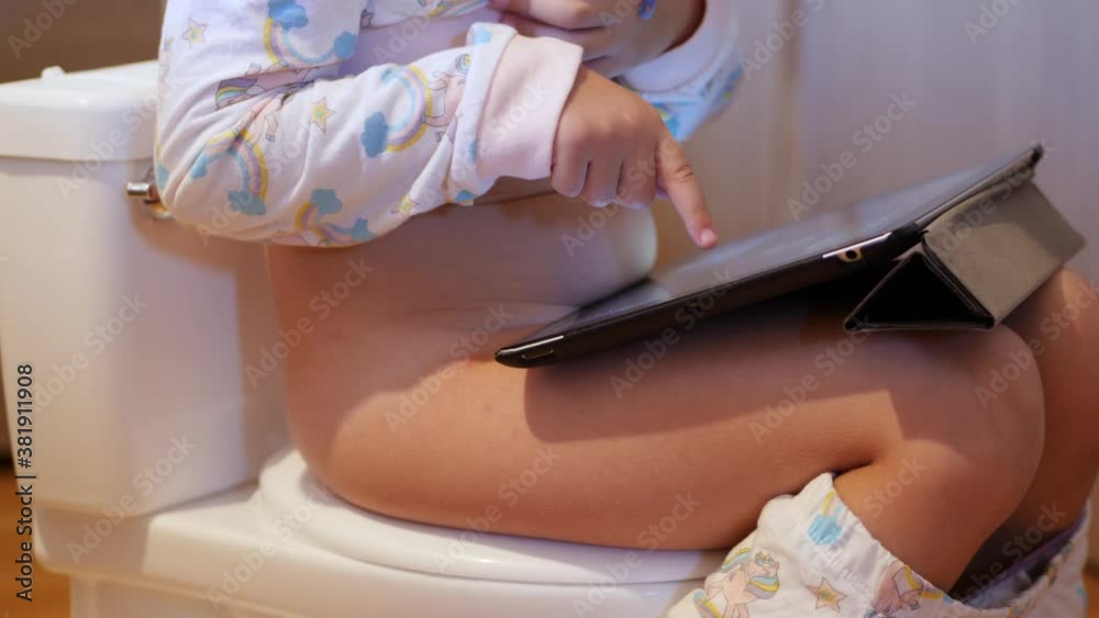 Little girl poops on toilet-shaped potty using tablet to relax ... 