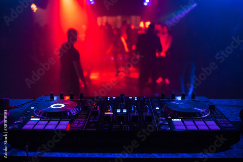 DJ console for mixing music with blurry people dancing at a nightclub party