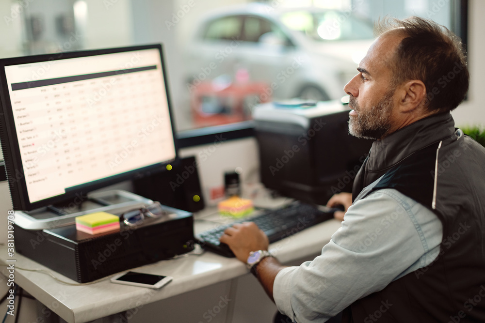 Male foreman working on desktop PC in auto repair office. Male foreman working on desktop PC in auto repair office.