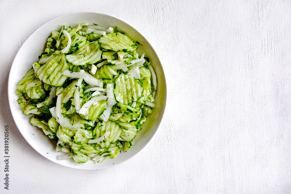 Homemade sauerkraut salad of sliced cucumbers in a bowl on a gray background. Fermented vegetables. Vegetarian vegan food. Healthy food, seasonal preservation of vegetables. Top view. Copy space.