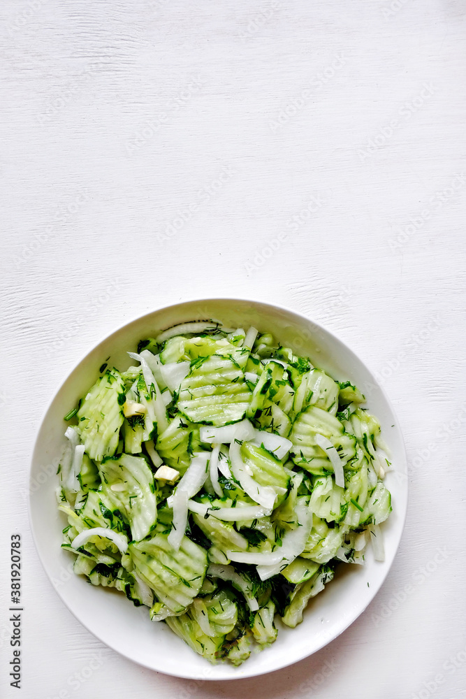 Homemade sauerkraut salad of sliced cucumbers in a bowl on a gray background. Fermented vegetables. Vegetarian vegan food. Healthy food, seasonal preservation of vegetables. Homemade sauerkraut salad of sliced cucumbers in a bowl on a gray background. Fermented vegetables. Vegetarian vegan food. Healthy food, seasonal preservation of vegetables.