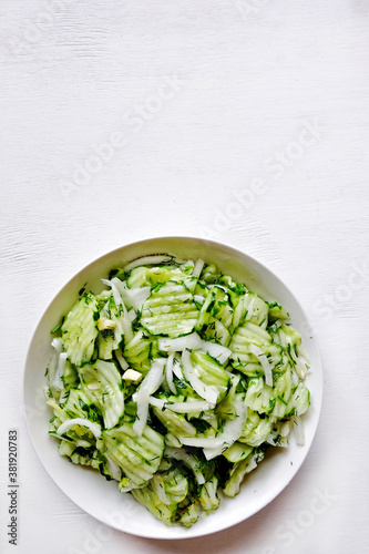 Homemade sauerkraut salad of sliced cucumbers in a bowl on a gray background. Fermented vegetables. Vegetarian vegan food. Healthy food, seasonal preservation of vegetables. 