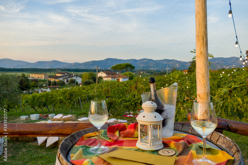 Fototapeta premium Picnic and wine tasting at sunset in the hills of Italy, Tuscany. Vineyards and open nature in the summer. Romantic dinner, fruit and wine.
