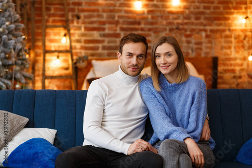 Portrait of beautiful smiling couple hugging at Christmas eve. Beautiful young couple at home enjoying spending time together. Winter holidays, Christmas celebrations, New Year concept. © YURII MASLAK