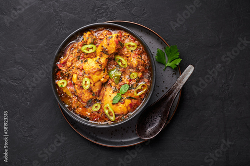 A Chicken Patiala in black bowl on dark slate table top. Murg Patiala is indian cuisine curry dish with chicken meat, spices, curd and cashew nut paste. Asian food and meal. Top view