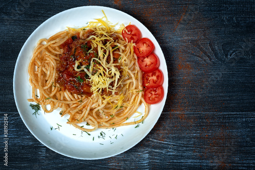 Traditional spaghetti pasta in a plate on a dark background . The view from the top .