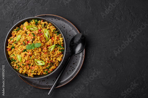 Masala Egg Bhurji or Muttai Podimas in black bowl on dark slate table top. Anda Bhurji is indian cuisine scrambled eggs dish with spices. Asian food and meal. Copy space