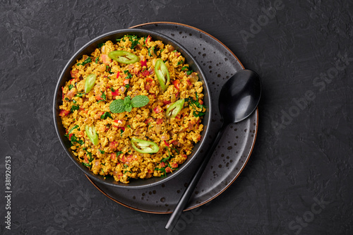 Masala Egg Bhurji or Muttai Podimas in black bowl on dark slate table top. Anda Bhurji is indian cuisine scrambled eggs dish with spices. Asian food and meal. Top view