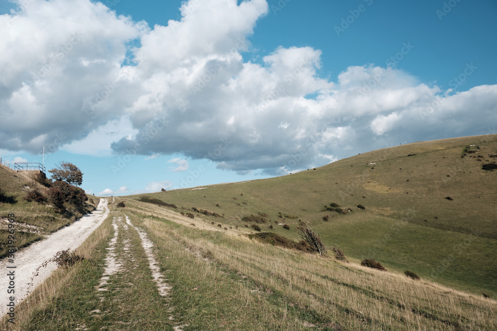 A chalk pathway along the South Downs Way in Sussex near Alfriston. Blue skies with low cumulus cloud