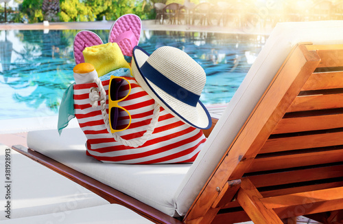Obraz na plátne Beach bag with accessories on sun lounger near swimming pool in luxury resort