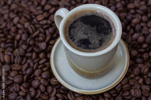 Black coffee in light brown cup on coffee beans background