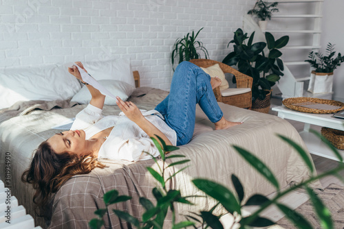 Young woman is lying in her bedroom reading documents photo