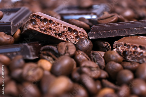 Close-up of dark roasted coffee beans and chocolate background. Aromatic coffee grains and sweet choco pieces macro photography,