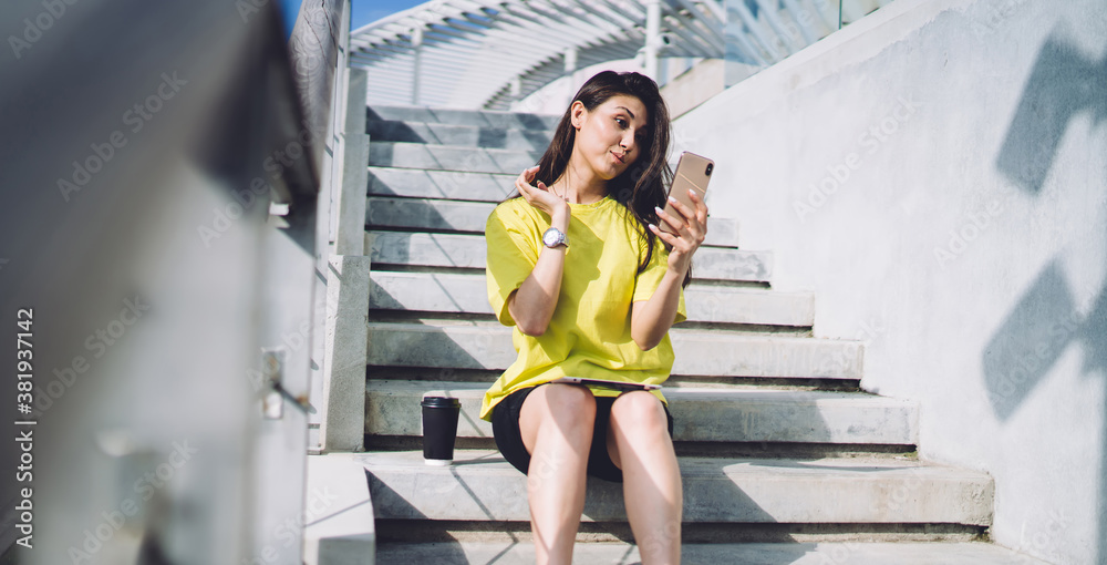 Obraz premium Young woman with smartphone on stairs taking funny selfie