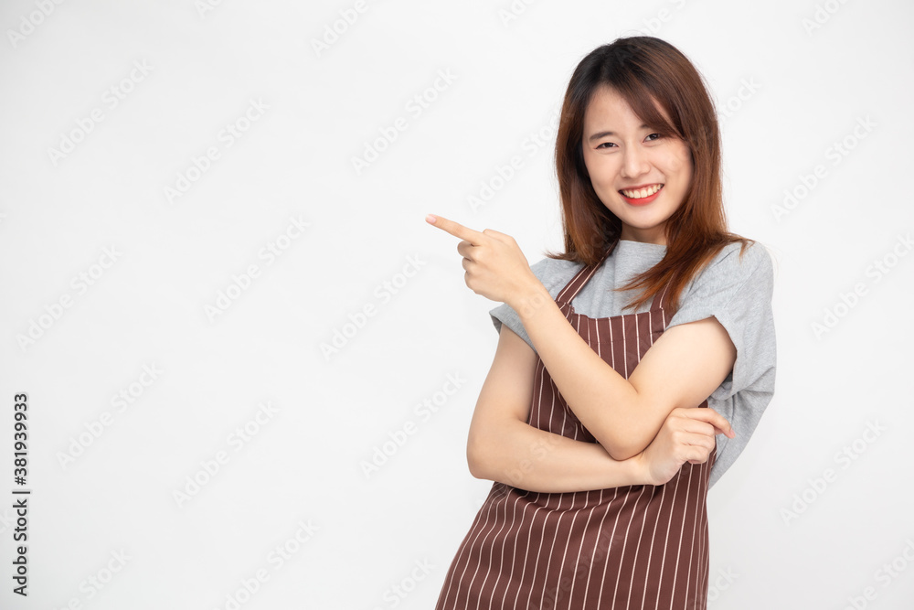 Portrait of Asian woman workers fresh market with brown apron standing and pointing finger to something isolated on white background Portrait of Asian woman workers fresh market with brown apron standing and pointing finger to something isolated on white background