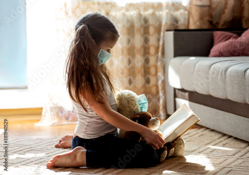 Little girl sitting with soft toys in a mask