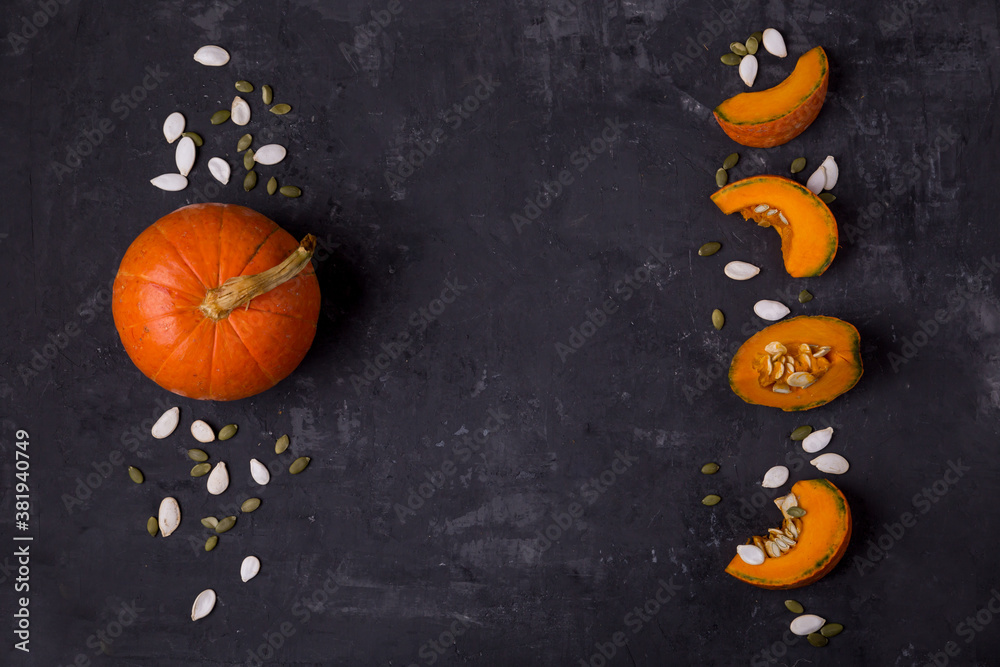 Pumpkin whole and in parts, pumpkin seeds. Layout on top. Dark background with copy space