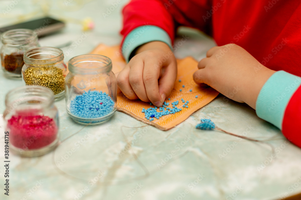 little girl weaves from beads. Needlework
little girl weaves from beads. Needlework