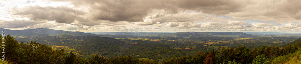 Panoramic view if Shenandoah valley observed from a scenic overlook by skyline drive. image features vast forests covering hills and mountains of blue ridge mountain range.
