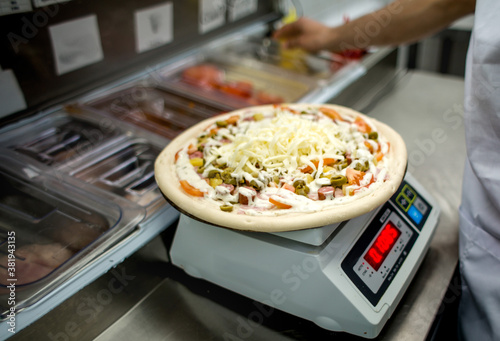 
the chef prepares pizza. weighs the ingredients
