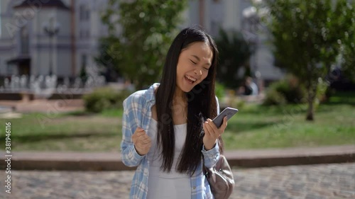Yes! I won! This is a success! Asian woman with smartphone rejoices at success. 4K