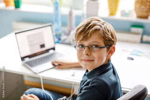 Canvas Print Kid boy with glasses learning at home on laptop for school
