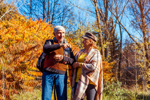 Fall activities. Senior family couple walking in autumn park. Man and woman enjoying nature outdoors talking