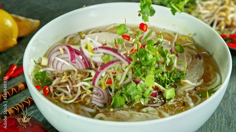 Super Slow Motion Detail Shot of Ingredients Falling into Chicken Pho Soup at 1000 fps.