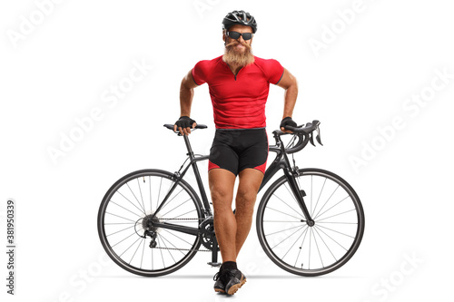 Full length portrait of a bearded cyclist with helmet and glasses leaning on a road bicycle