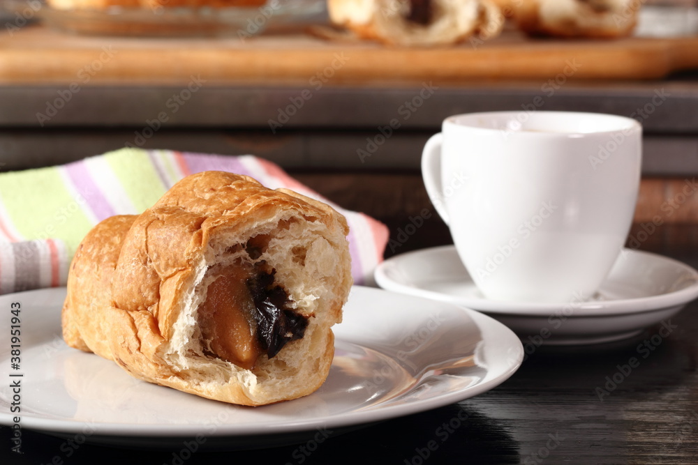 Croissant with cocoa and peanut fillings and coffee cup Croissant with cocoa and peanut fillings and coffee cup