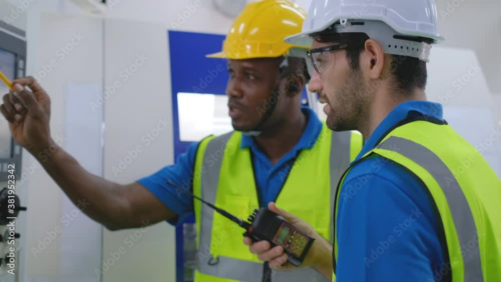 Two factory worker men discuss together about machine working in workplace area. Concept of good process and management for industrial business. Two factory worker men discuss together about machine working in workplace area. Concept of good process and management for industrial business.