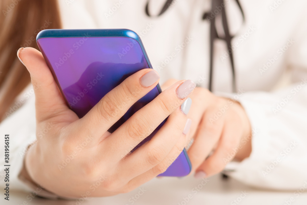 girl uses the smartphone at the table, typing SMS, looks at social media, mobile apps girl uses the smartphone at the table, typing SMS, looks at social media, mobile apps