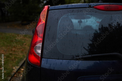 Back window of dark car parked on the street in autumn rainy day, rear view. Mock-up for sticker or decals