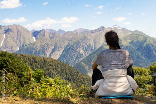 Travel, adventure and trekking by Hiking in the mountains. girl is sitting on a scenic peak, looking at the landscape