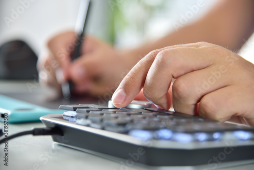 Graphic designer hand using digital control wheel keyboard.