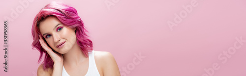 young woman with colorful hair and makeup touching face isolated on pink, panoramic shot