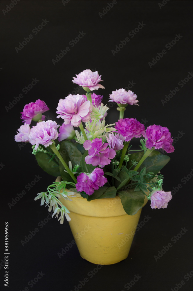 pot with artificial lilac and pink flowers, isolated on black background