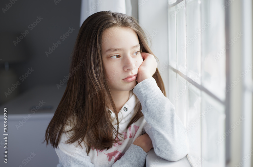 portrait of a young teenage girl looking out the window with her face against her hand portrait of a young teenage girl looking out the window with her face against her hand